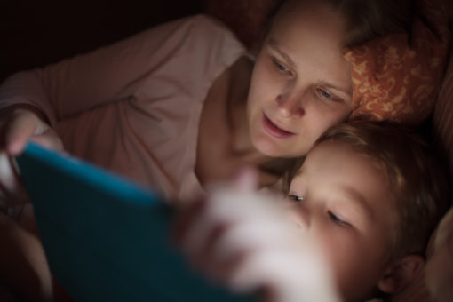 Mother and son with pad in bed at night